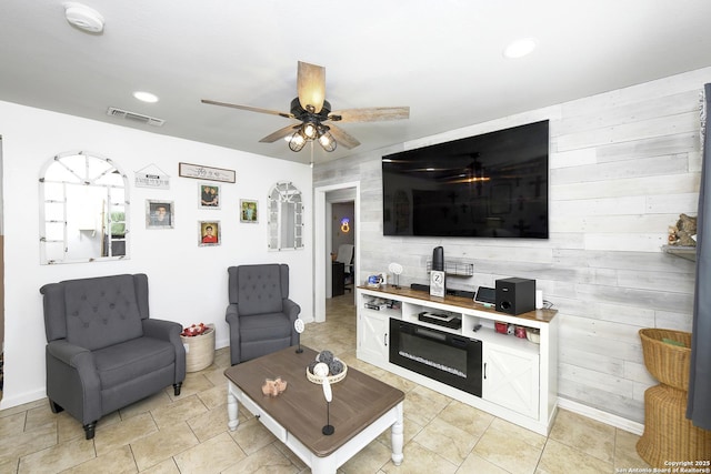 living room featuring ceiling fan, recessed lighting, wooden walls, visible vents, and baseboards