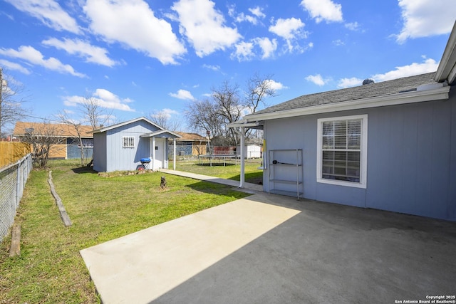 view of yard with a fenced backyard, a trampoline, an outbuilding, and a patio