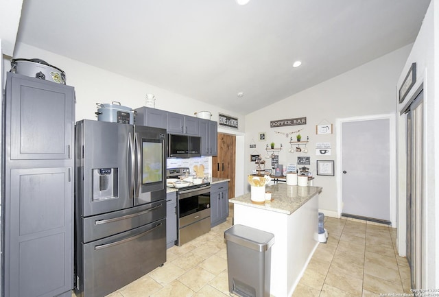 kitchen with light tile patterned floors, light stone countertops, stainless steel appliances, vaulted ceiling, and a center island