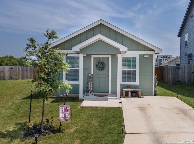 bungalow-style house with board and batten siding, fence, and a front lawn