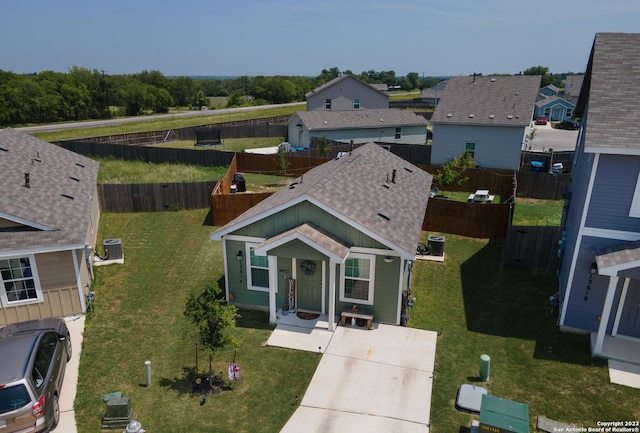 view of front of property featuring roof with shingles, central AC unit, a front yard, fence, and a residential view