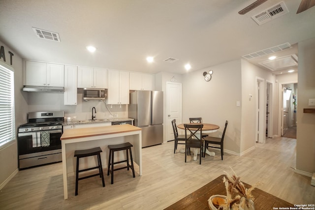 kitchen featuring butcher block countertops, visible vents, stainless steel appliances, and a sink