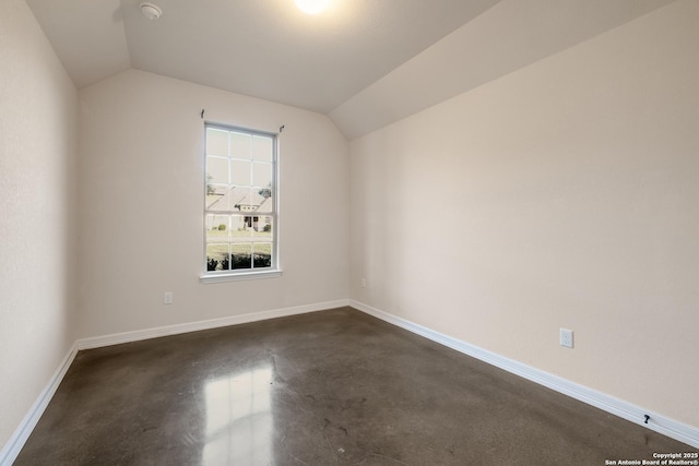 bonus room with vaulted ceiling, finished concrete flooring, and baseboards