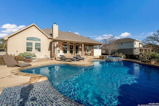 view of pool with a pool with connected hot tub, fence, and a patio