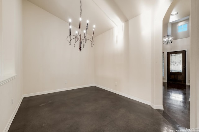 unfurnished dining area with baseboards, a high ceiling, an inviting chandelier, and finished concrete floors