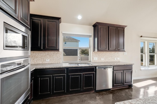 kitchen featuring stainless steel appliances, a sink, light stone countertops, and decorative backsplash