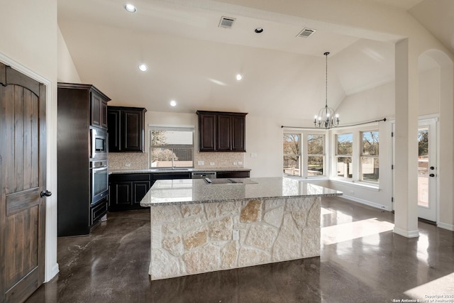 kitchen featuring a sink, visible vents, appliances with stainless steel finishes, backsplash, and a large island with sink