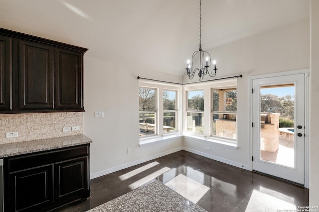 unfurnished dining area featuring a notable chandelier, baseboards, concrete flooring, and a wealth of natural light