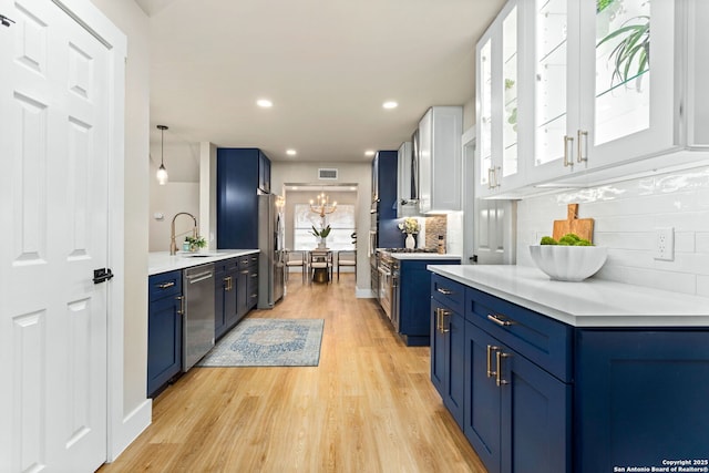 kitchen featuring stainless steel appliances, light wood-type flooring, a sink, and blue cabinetry