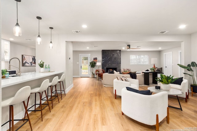 living room featuring recessed lighting, visible vents, light wood finished floors, and a premium fireplace