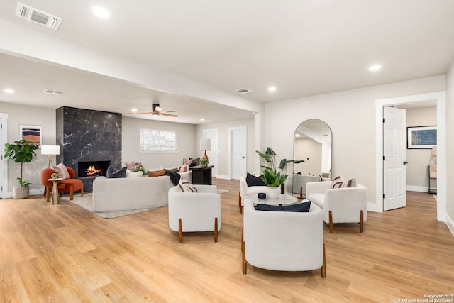 living area with light wood-style floors, visible vents, arched walkways, and a high end fireplace