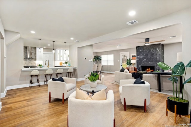 living area with light wood finished floors, baseboards, visible vents, a fireplace, and recessed lighting