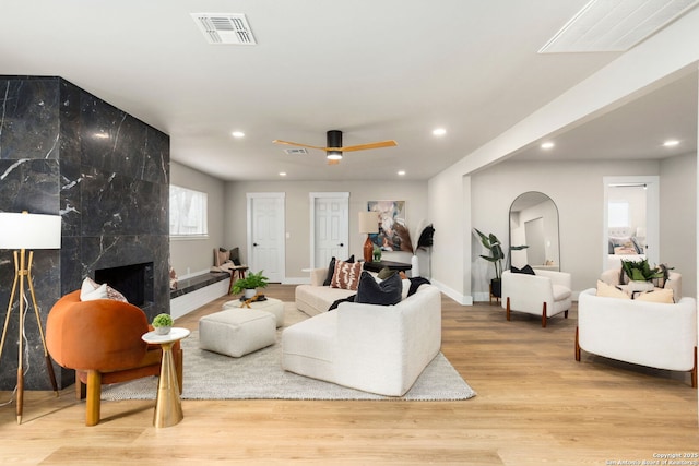 living area with arched walkways, wood finished floors, visible vents, and a high end fireplace