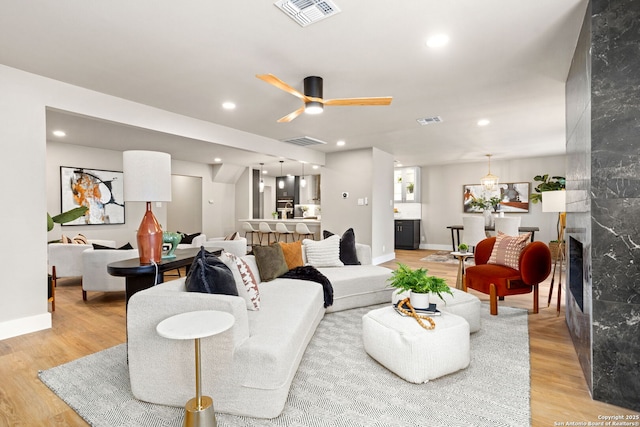 living room featuring light wood-style floors, a high end fireplace, and visible vents