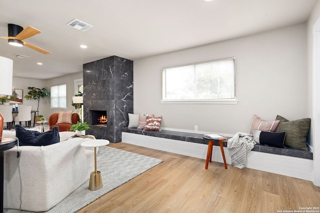 living area with a fireplace, visible vents, wood finished floors, and recessed lighting