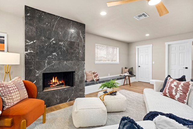 living room with ceiling fan, recessed lighting, wood finished floors, a high end fireplace, and visible vents