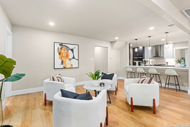 living area featuring light wood-style floors, recessed lighting, visible vents, and baseboards