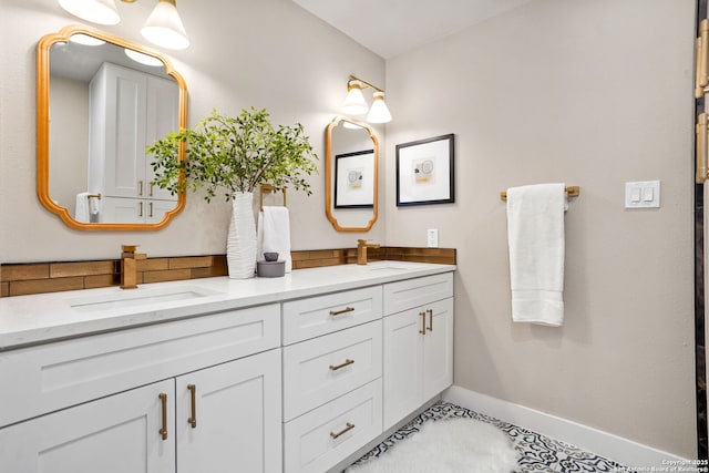 full bath with double vanity, a sink, and baseboards