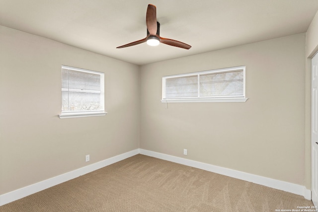 spare room with baseboards, ceiling fan, and light colored carpet