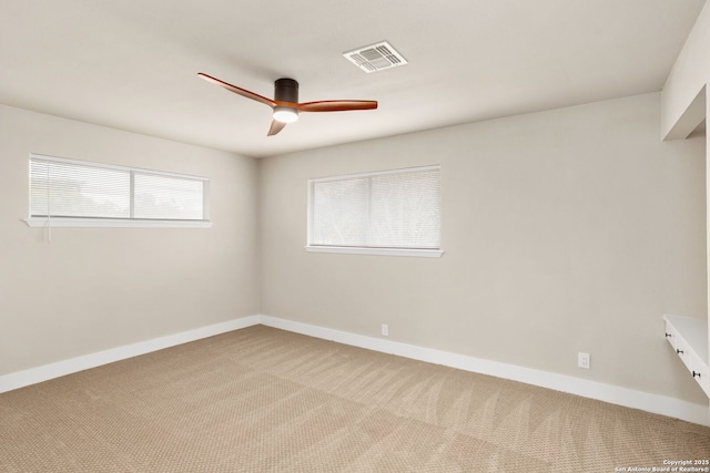 carpeted empty room featuring a ceiling fan, visible vents, and baseboards