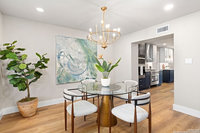 dining space featuring a notable chandelier, light wood-style flooring, visible vents, and baseboards