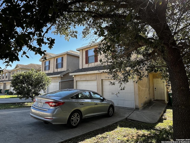 view of property featuring concrete driveway, an attached garage, and stucco siding