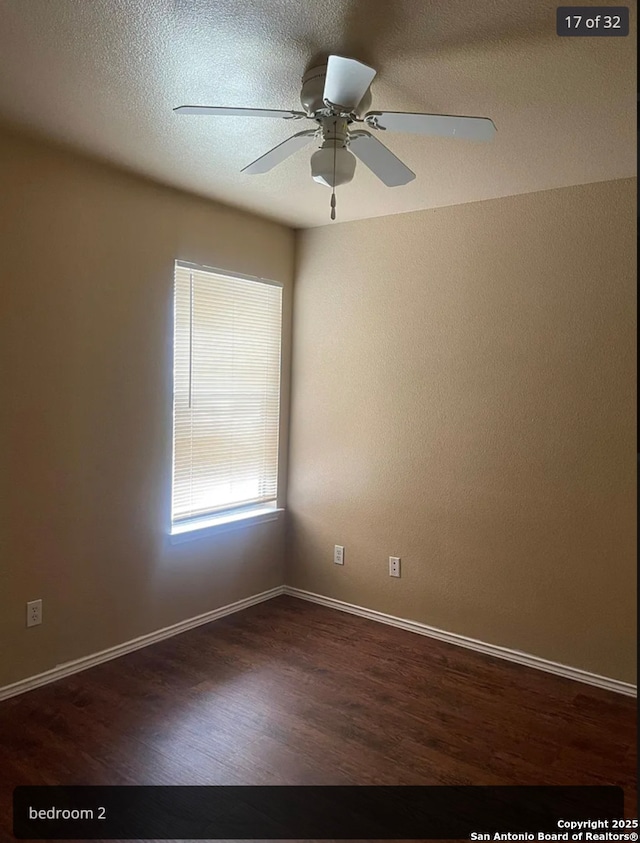 unfurnished room featuring a textured ceiling, baseboards, dark wood finished floors, and a ceiling fan