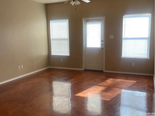 interior space featuring a ceiling fan, baseboards, and concrete flooring