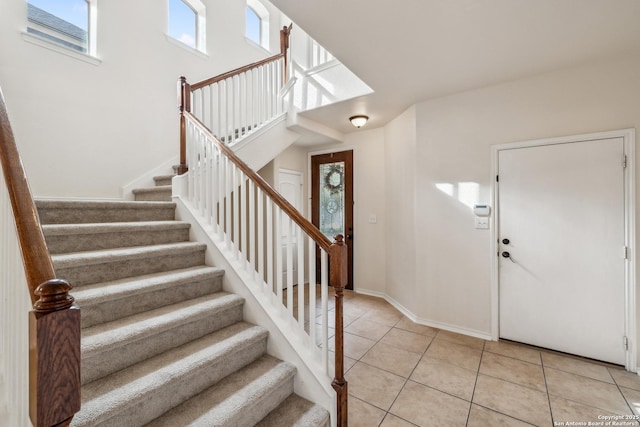 foyer entrance with light tile patterned floors, stairs, and baseboards