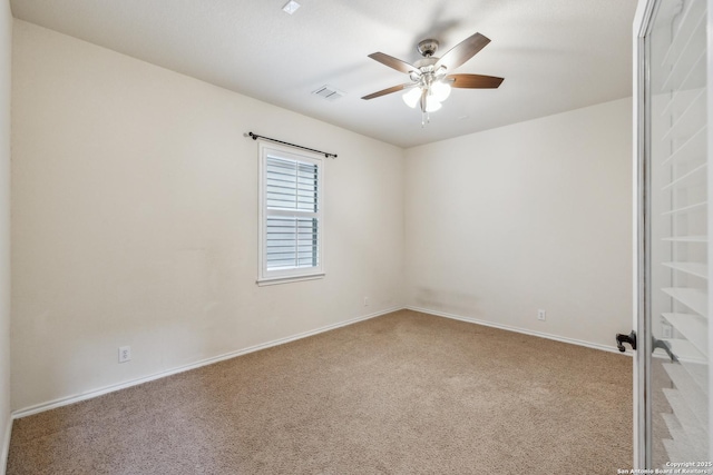 carpeted empty room with ceiling fan, visible vents, and baseboards