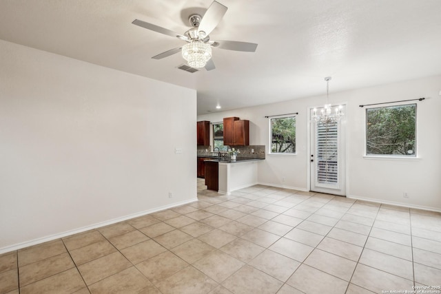 spare room with light tile patterned floors, baseboards, visible vents, a sink, and ceiling fan with notable chandelier