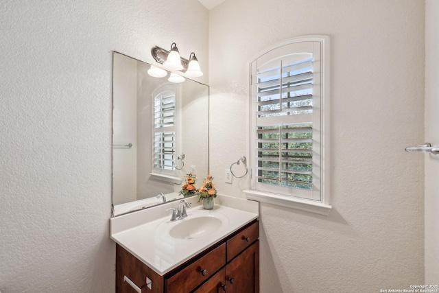 bathroom featuring a textured wall, a wealth of natural light, and vanity