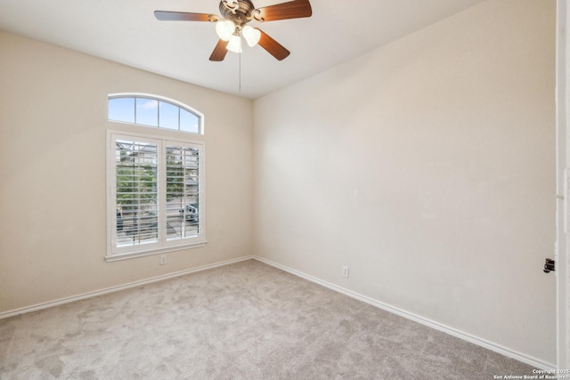 carpeted spare room with a ceiling fan and baseboards