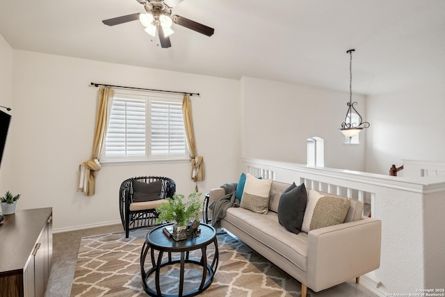 living area featuring carpet floors, ceiling fan, and baseboards