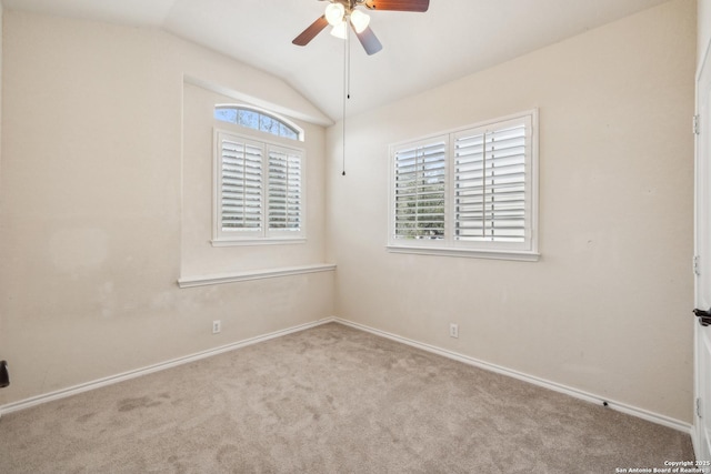 carpeted spare room with baseboards, vaulted ceiling, and a ceiling fan