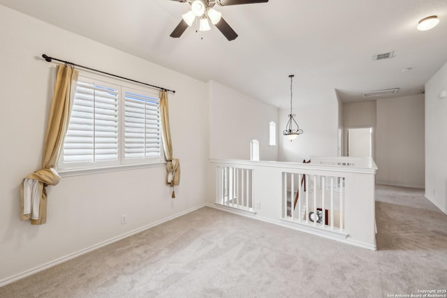 carpeted empty room with a ceiling fan, visible vents, and baseboards