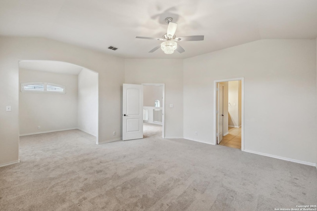 unfurnished bedroom with arched walkways, visible vents, light carpet, vaulted ceiling, and baseboards