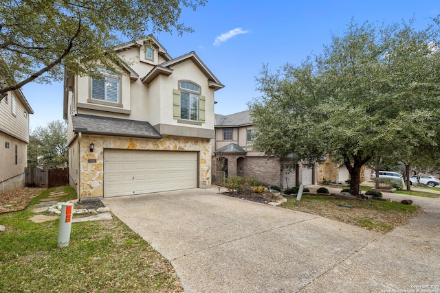 traditional-style home featuring an attached garage, fence, stone siding, driveway, and stucco siding