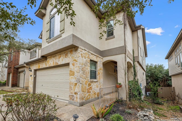 view of front of property with stone siding, an attached garage, and stucco siding