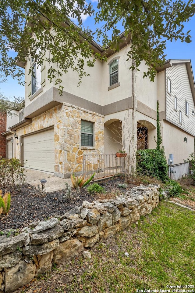 view of front of property with an attached garage, stone siding, and stucco siding