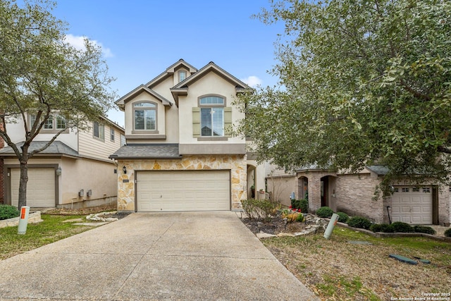 view of front facade featuring a garage, concrete driveway, stone siding, and stucco siding