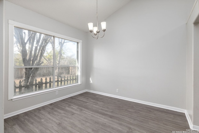 unfurnished dining area featuring lofted ceiling, dark wood-style floors, baseboards, and an inviting chandelier