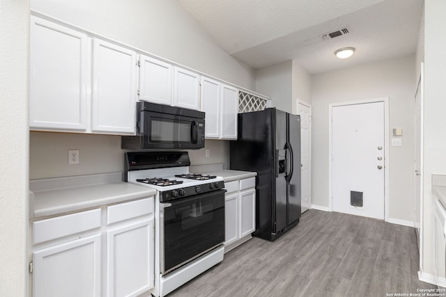 kitchen featuring visible vents, white cabinets, light wood-style floors, light countertops, and black appliances