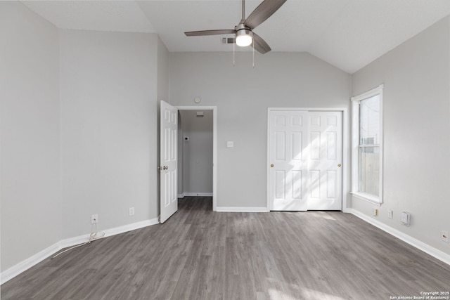 unfurnished bedroom with lofted ceiling, a closet, visible vents, wood finished floors, and baseboards