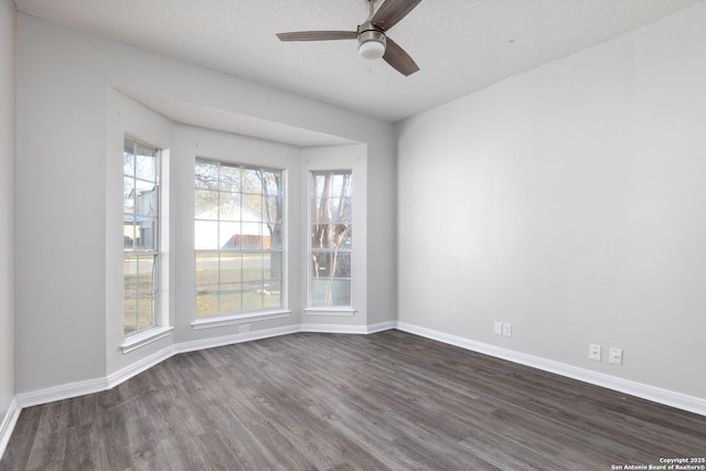 unfurnished room featuring a ceiling fan, a textured ceiling, baseboards, and dark wood-type flooring