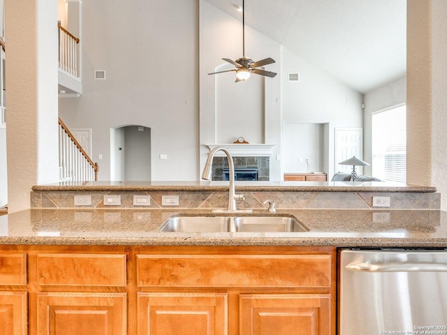 kitchen featuring a fireplace, a sink, visible vents, light stone countertops, and dishwasher