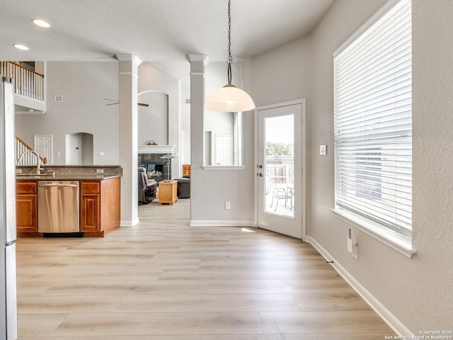 kitchen with a fireplace, baseboards, light wood-type flooring, brown cabinets, and dishwasher