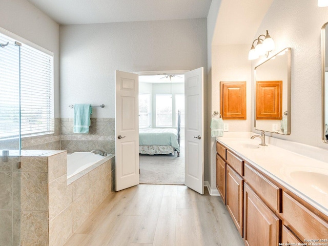 bathroom featuring a garden tub, double vanity, connected bathroom, a sink, and wood finished floors