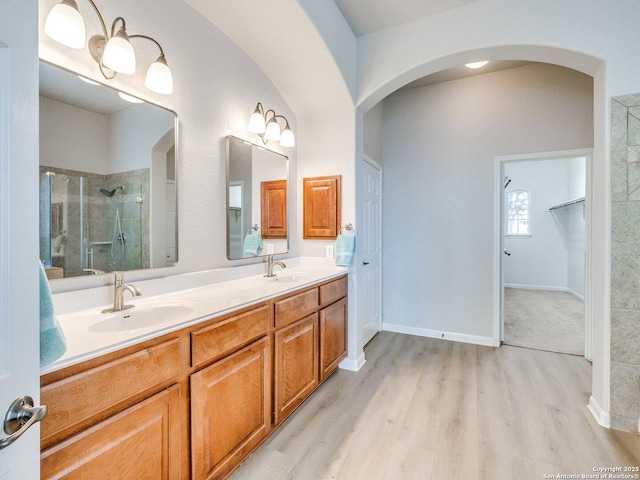 bathroom with a sink, double vanity, wood finished floors, and a shower stall