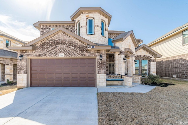 french provincial home with stone siding, brick siding, an attached garage, and concrete driveway